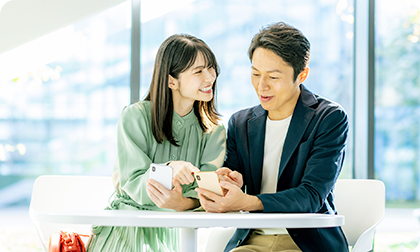 外出先のカフェでスマートフォンを利用する男女